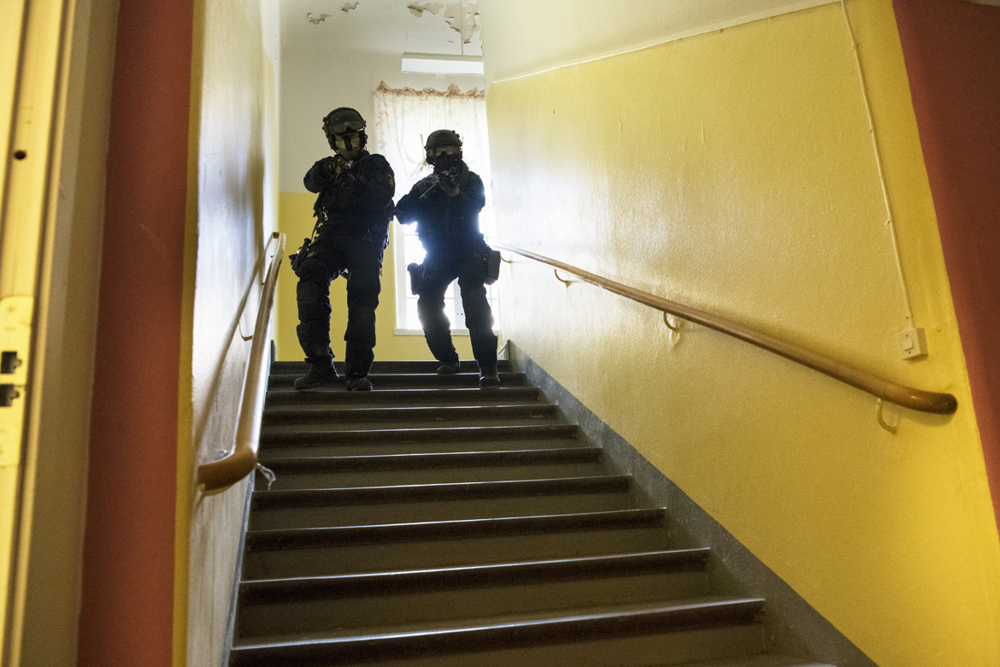 Jenny och en manlig kollega kommer ner med framåtriktade vapen i en trappa i övningsbyggnaden. Foto.