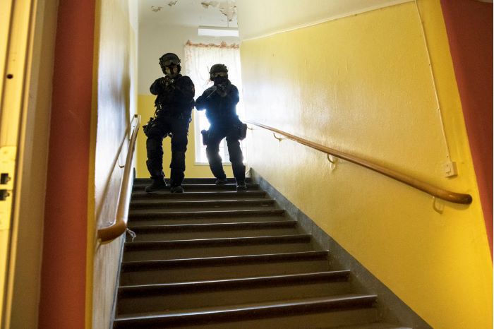 Jenny och en manlig kollega kommer ner med framåtriktade vapen i en trappa i övningsbyggnaden. Foto.