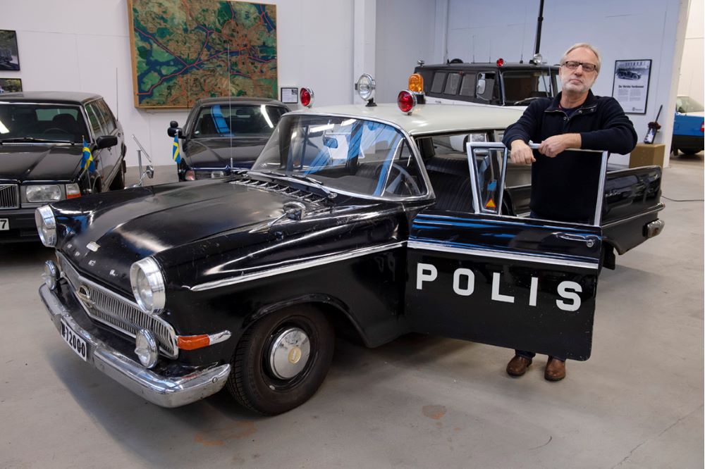 Föredetta polisen Bengt Svenson poserar bredvid Opel Kapitänen i lokalen för Polismuséets fordonssamling