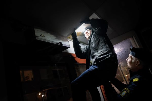 Polisen Henrik Herou hjälper områdespolisen Carl Olsson att komma upp så han kan titta in under en takplatta. Foto.