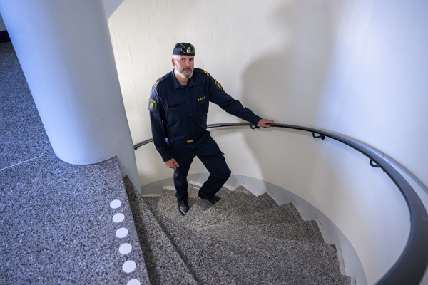 Kommunpolisen Christoffer Peyre går uppför en spiraltrappa i ett flerfamiljshus. Foto.