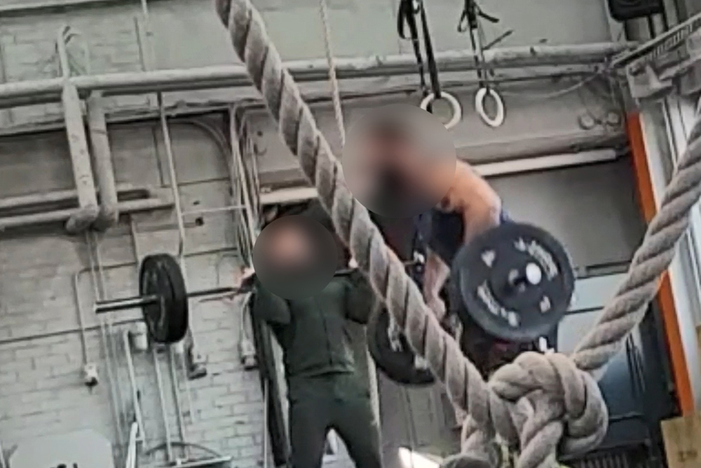 Två män med blurrade ansikten tränar tyngdlyftning i ett gym. Foto.