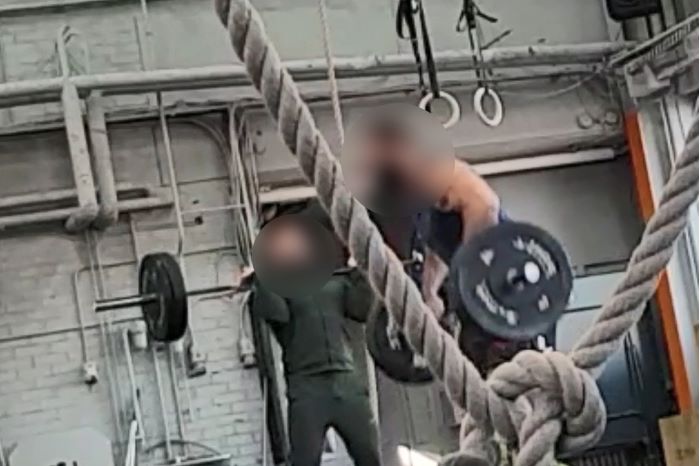 Två män med blurrade ansikten tränar tyngdlyftning i ett gym. Foto.