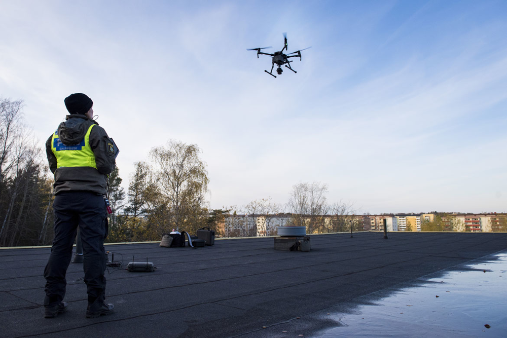 Uas-förare står på ett tak och kör drönare