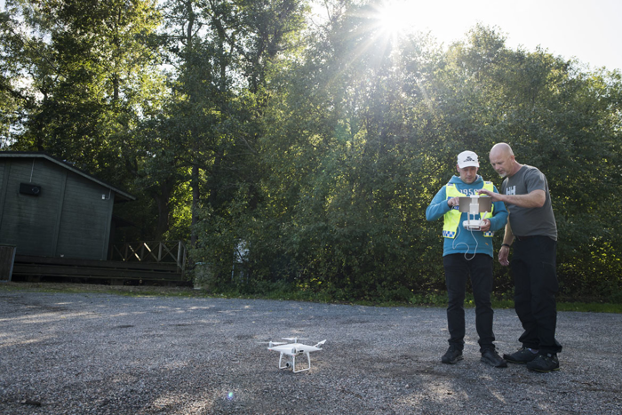 Tre män tittar på en skärm till en drönare