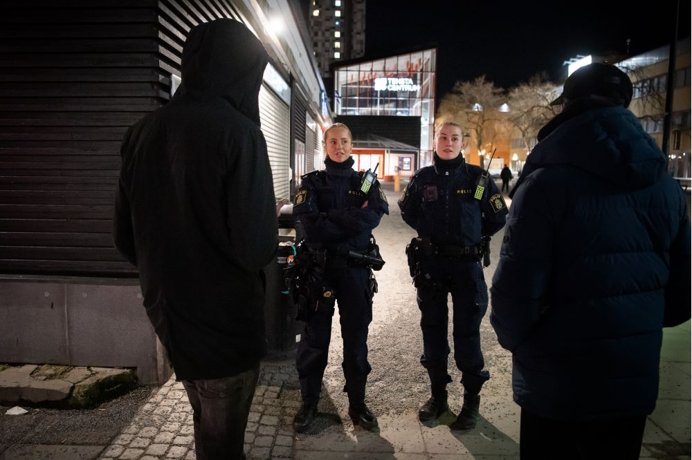 Stina och Amanda från lokalpolisområde Hisingen i Göteborg pratar med ett par män vid Tensta torg. Foto.