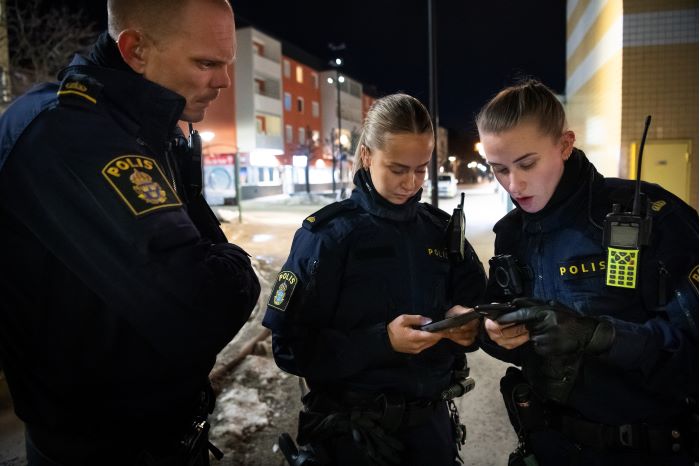 Poliserna Stina och Amanda från lokalpolisområde Hisingen står och tittar efter något i sina mobiler.  Foto.