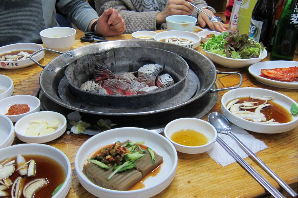 Koreansk grill med flera smårätter uppdukad på ett bord. Foto.
