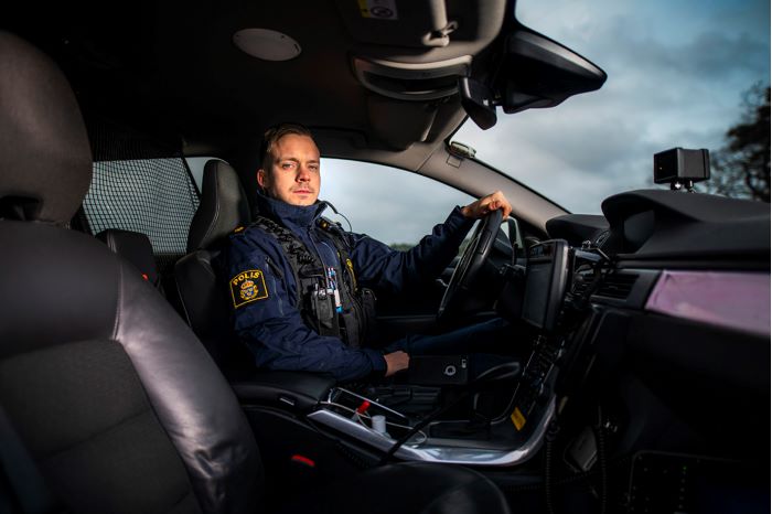 Polisen Fredrik sitter ensam på förarsidan i en polisbil, och tittar mot kameran