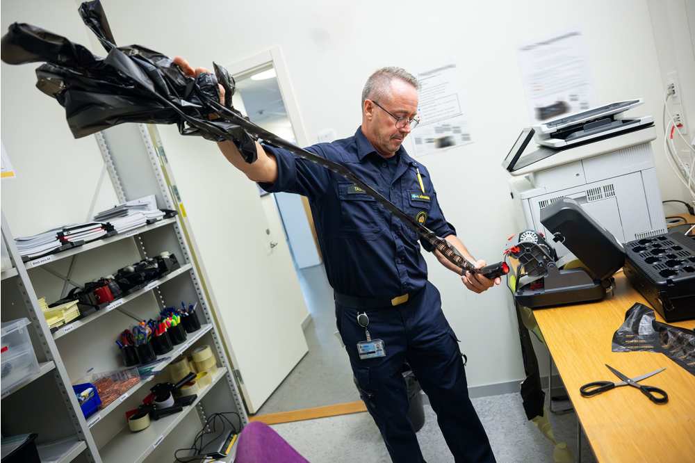 Glenn reder ut en lång remsa som fastnat i etikettmaskinen. Foto.