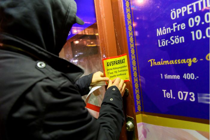 En gul klisterlapp med texten "Avspärrrat" sätts upp på dörren till thaimassagesalongen. Foto.