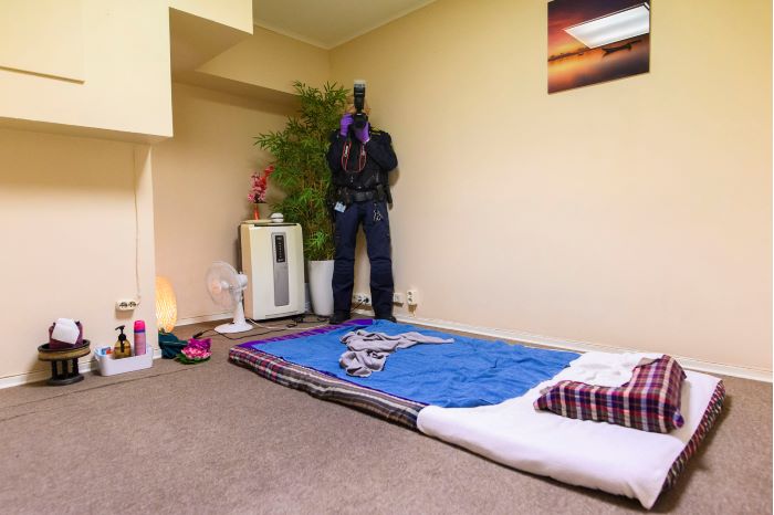 En kriminaltekniker fotograferar ett rum med en madrass på golvet. Foto.