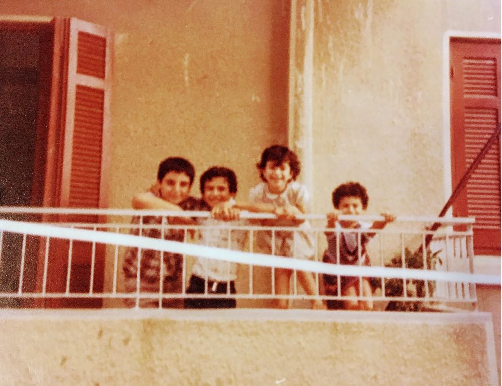 Ayman Aboulaich och hans systrar står tillsammans med grannpojken på en balkong. Foto.