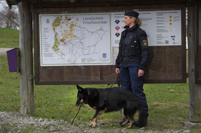 Hundföraren Jennie Güldenpfenning och hunden Tilya framför en informationstavla i Lassalyckans friluftsområde