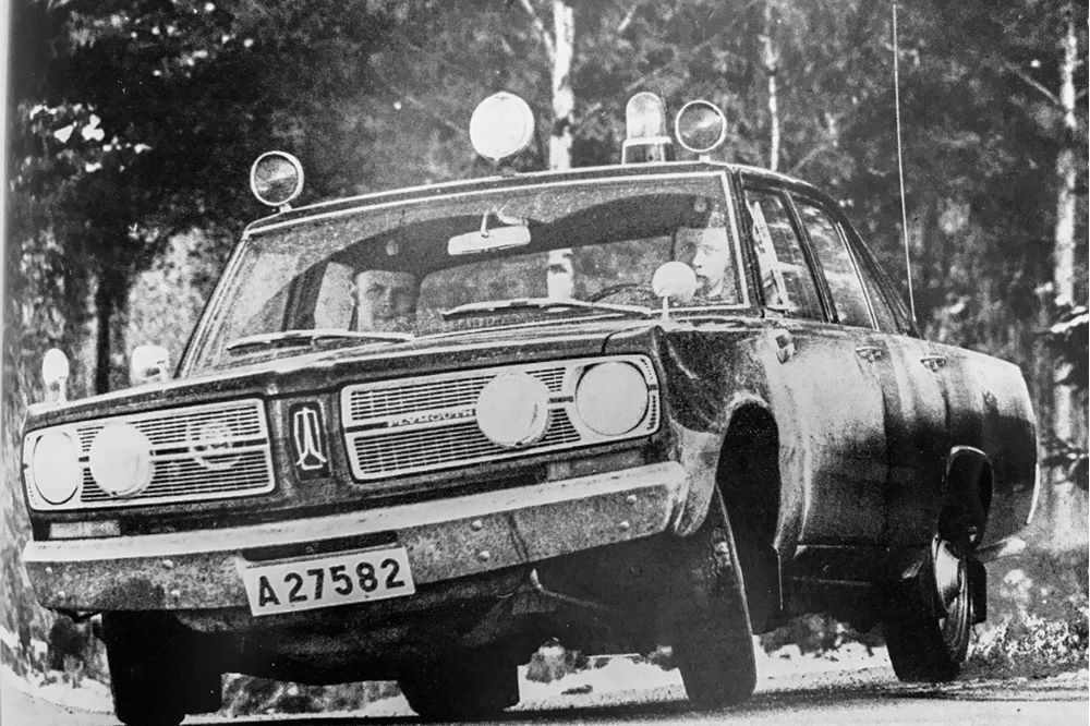 En polisbil av gammal modell med två poliser i. Foto.