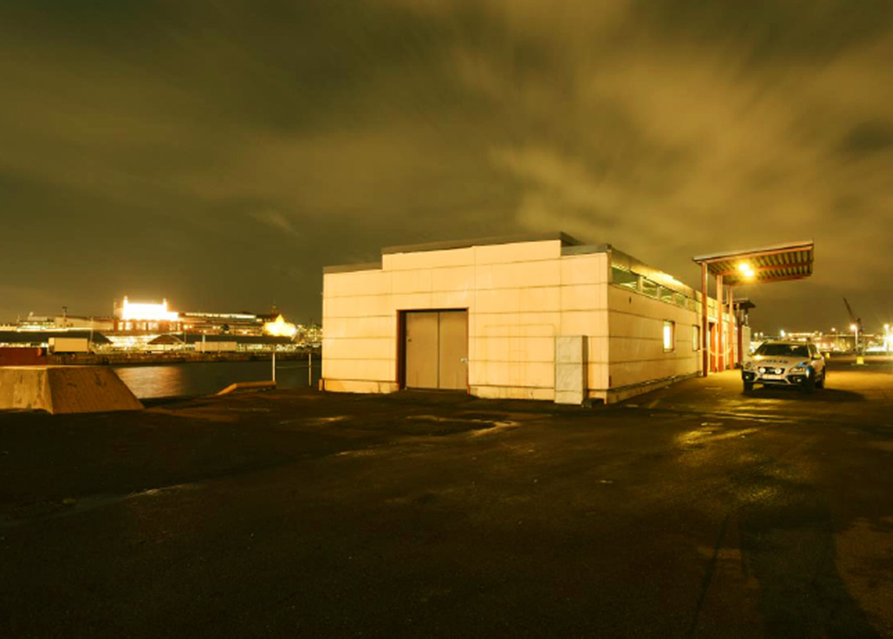 En lagerlokal i skymning med en polisbil stående utanför. Foto.