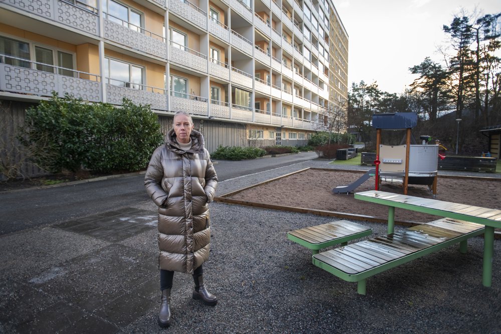 Elin Hernstedt, regionalt ansvarig i Stockholm, står utomhus på en lekplats på bakgården till ett flerfamiljshus. Foto.