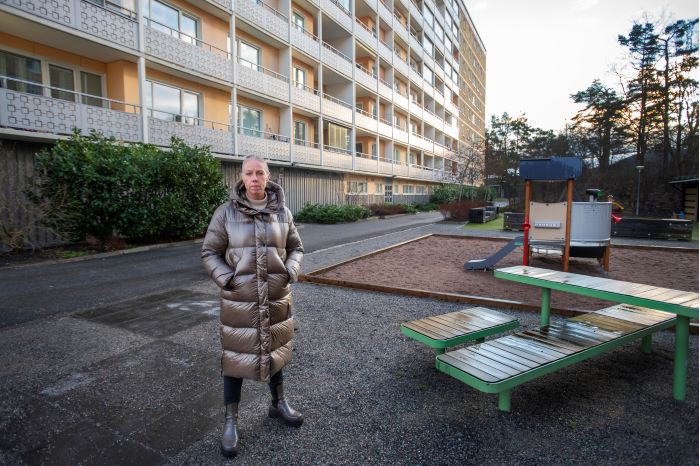 Elin Hernstedt, regionalt ansvarig i Stockholm, står utomhus på en lekplats på bakgården till ett flerfamiljshus. Foto.