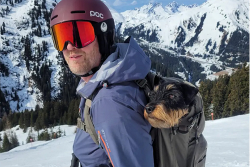 Ivan sitter i husses ryggsäck i skidbacken. Foto.