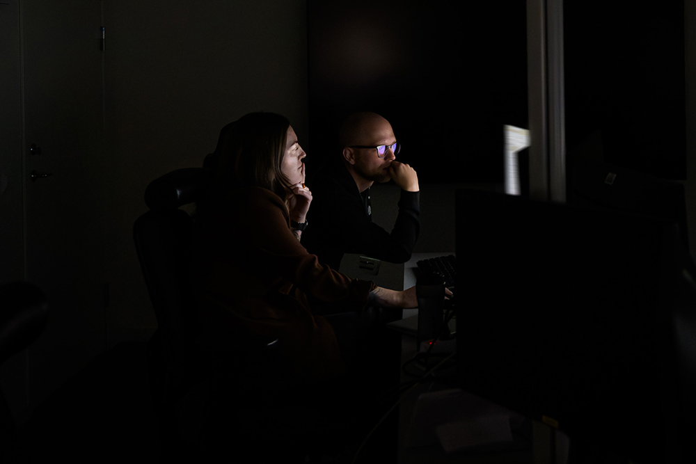 Två utredare på Isöb sitter framför en datorskärm i ett mörkt rum. Foto.