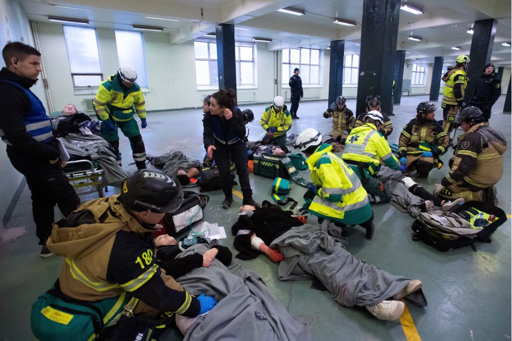 Akutsjukvårdare och räddningspersonal tar hand om skadade elever på golvet. Foto.