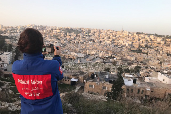 Sofia Zitouni står med ryggen mot kameran och tar själv en bild på utsikten över staden Hebron. Foto.