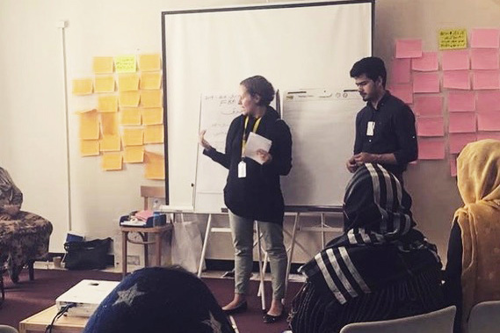 Sofia Zitouni står framför en whiteboard och talar till publiken bestående av kvinnliga fredsmedlare. Foto.