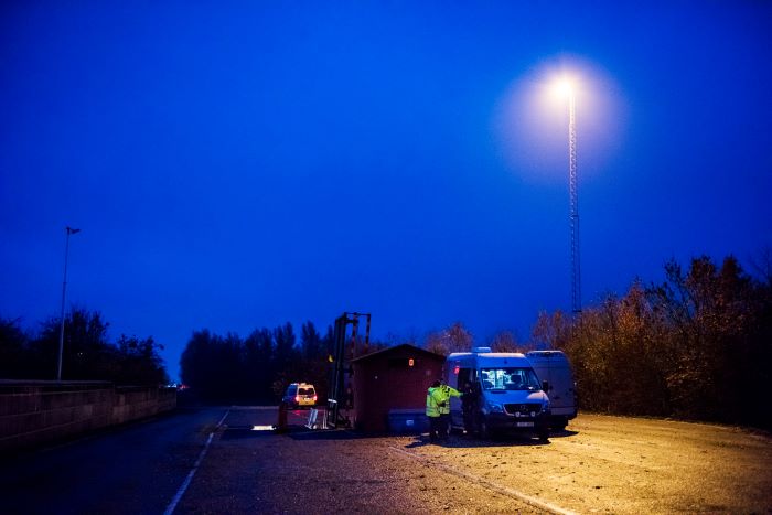 En bilinspektörsbuss står längs med en väg i skenet av en gatulampa i mörkret. Foto.