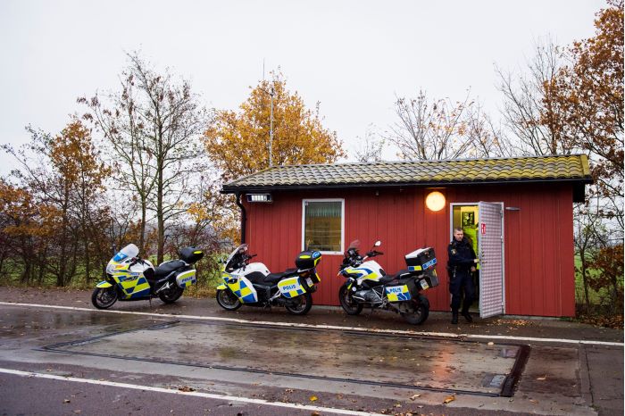 En röd stuga med tre polismotorcyklar framför. Foto.
