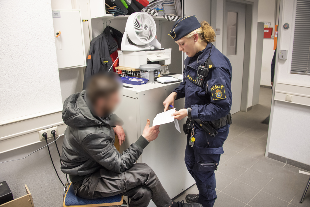 Uniformerad polis räcker en lapp till misstänkt snattare.