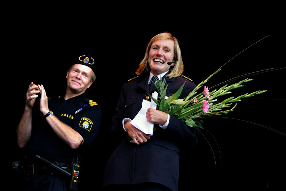Carin Götblad står bredvid en poliskollega och har blommor i famnen. Foto.