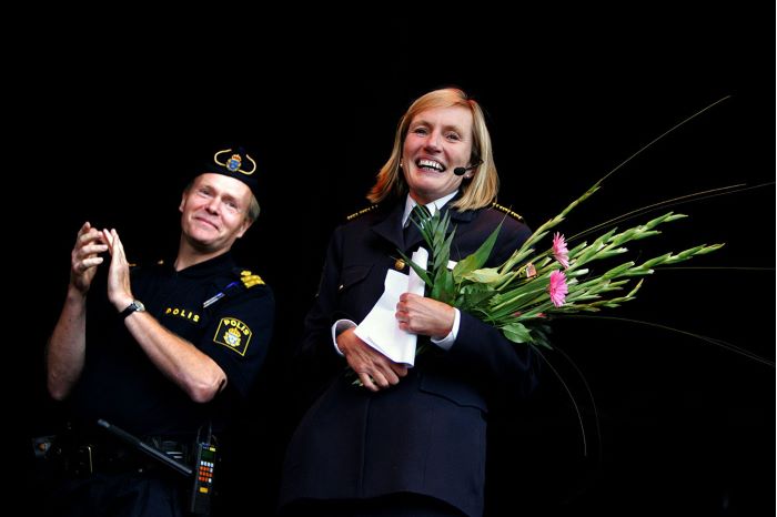 Carin Götblad står bredvid en poliskollega och har blommor i famnen. Foto.