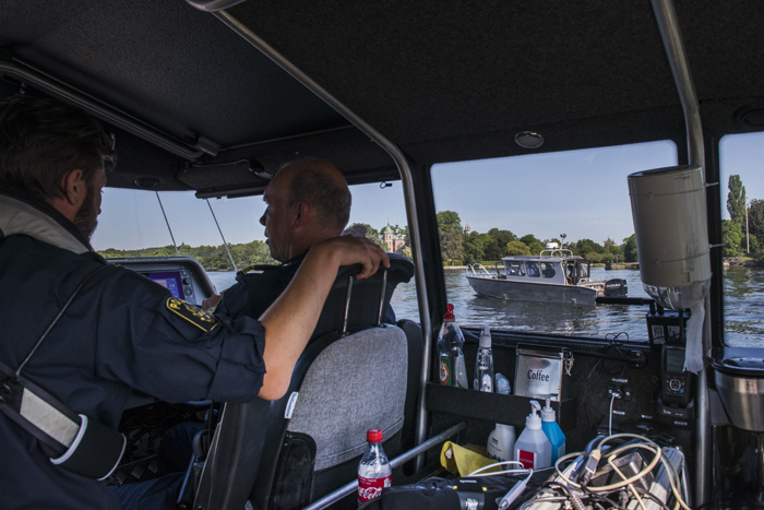 Genom fönstret på polisbåten ser man produktionsbolagets båt på vattnet. Foto.