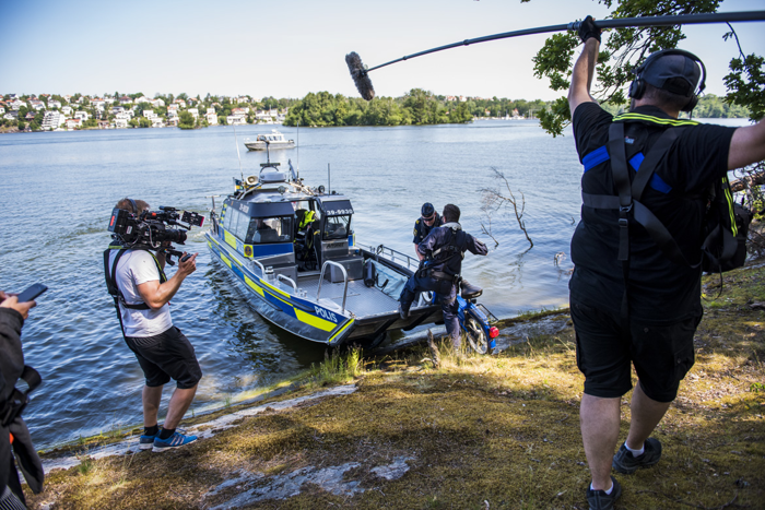 Sjöpoliserna bär upp en moped på polisbåten medan produktionsbolaget filmar och tar upp ljud. Foto.