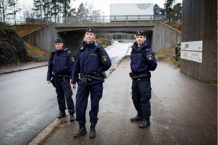 Tre områdespoliser framför en vägbro.