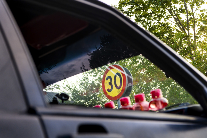 En hastighetsskylt med 30 angivet ses genom rutorna på a-traktorn. I framrutan ses fem rosa burkar. Foto.