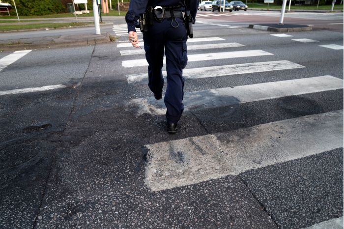 Underkroppen på en polis när denna går över ett övergångsställe. Foto.