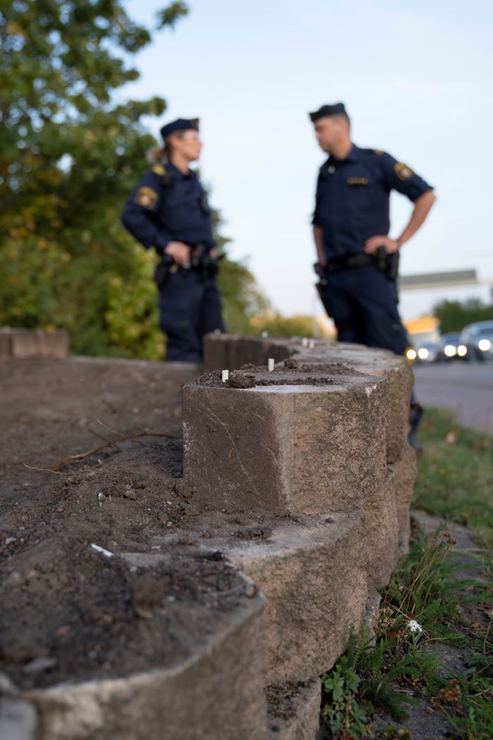 En stor gatsten på marken, med poliserna Malin Morän och Johannes Schultz i bakgrunden. Foto.