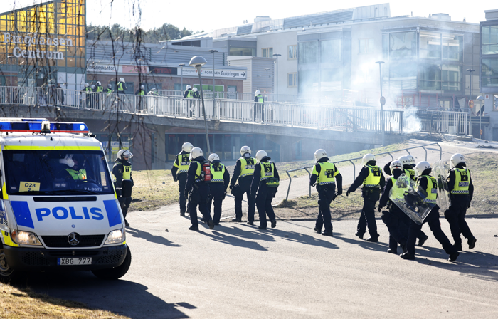 En lång rad av poliser med hjälm och vissa med sköld ses gående mot centrum. Foto.